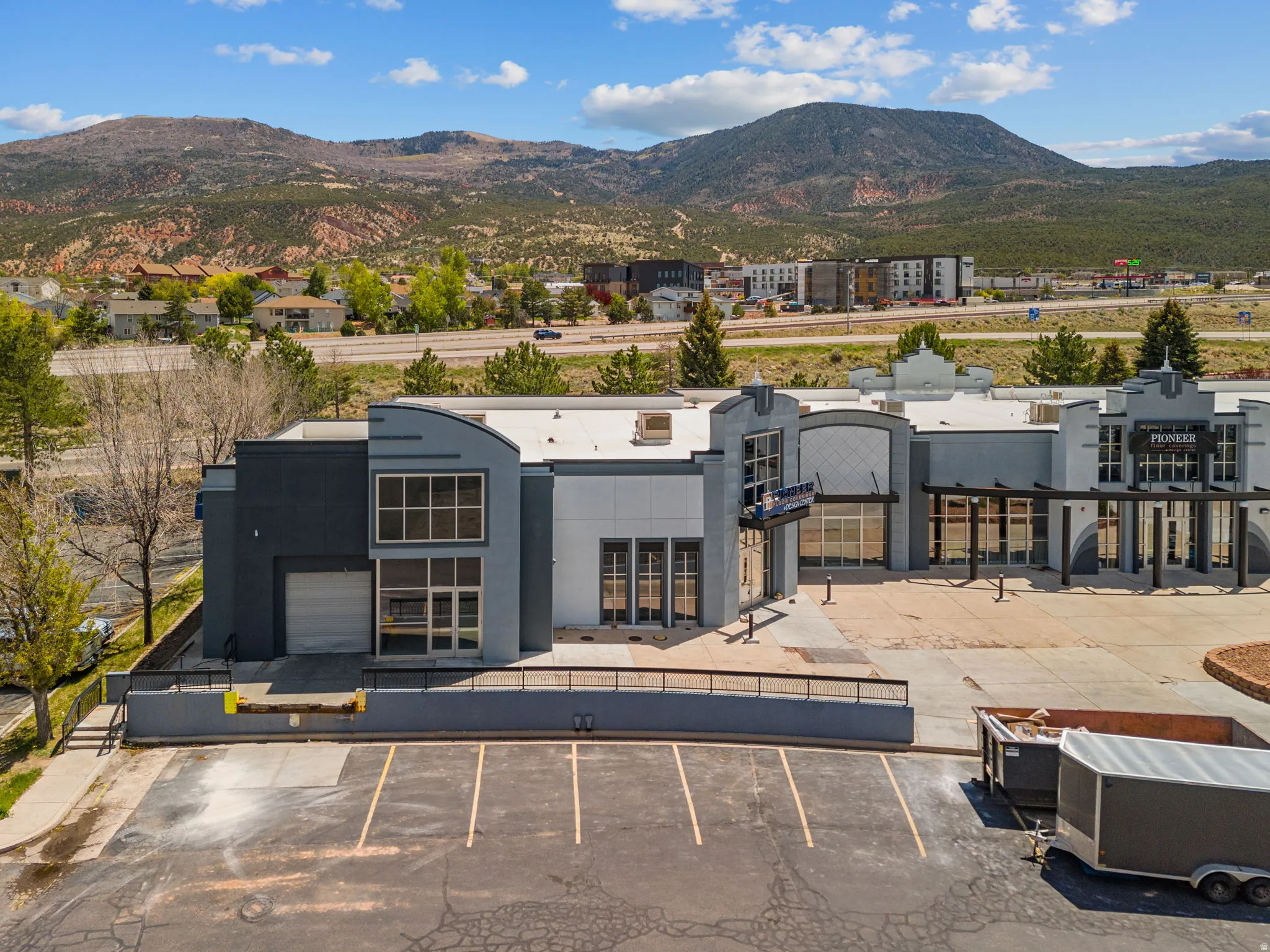 Commercial building featuring a flat roofline, multi-pane windows, and a large paved parking area
