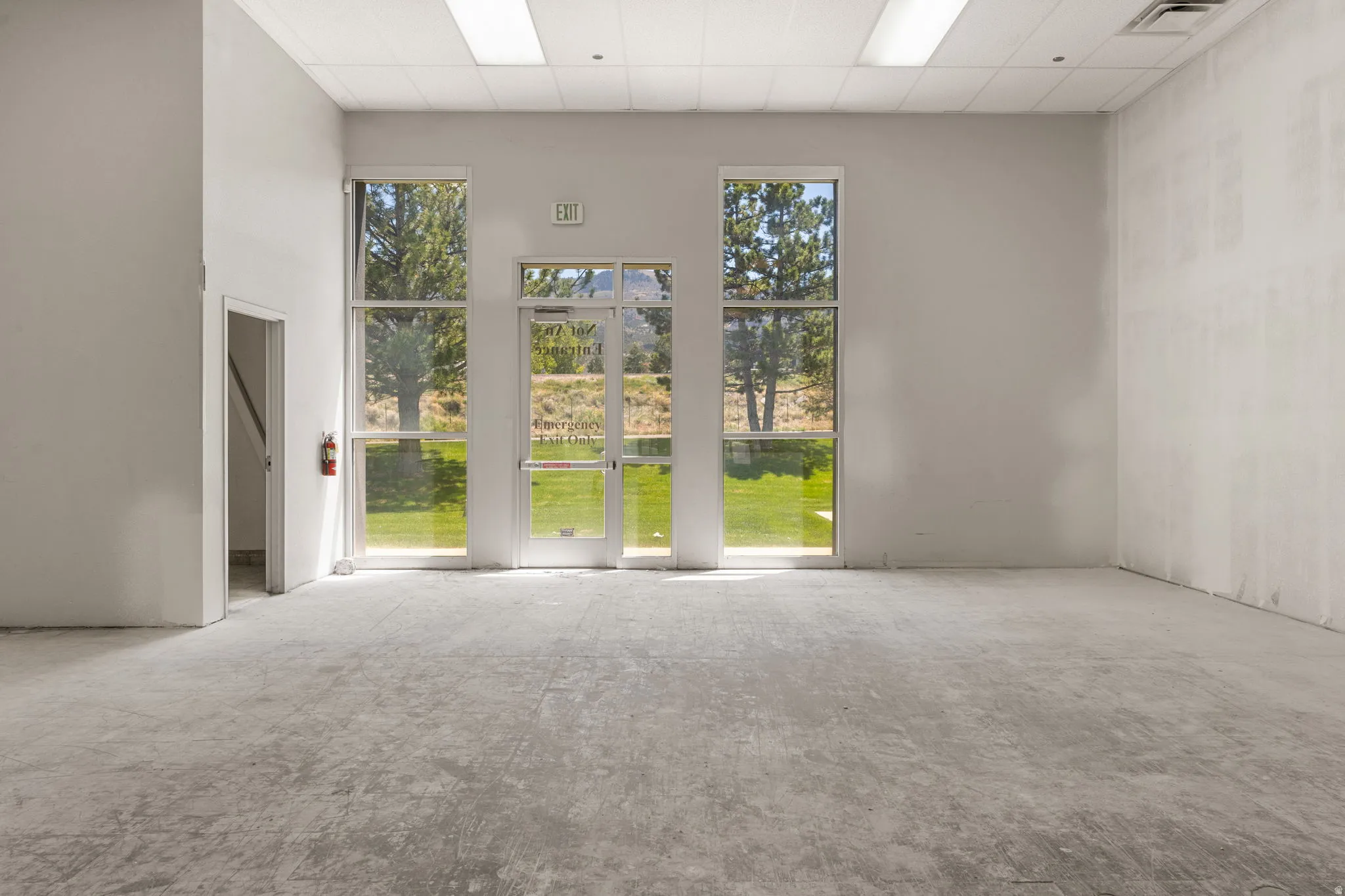 Spacious room featuring multiple large windows and a glass-paneled entry door, providing abundant natural light