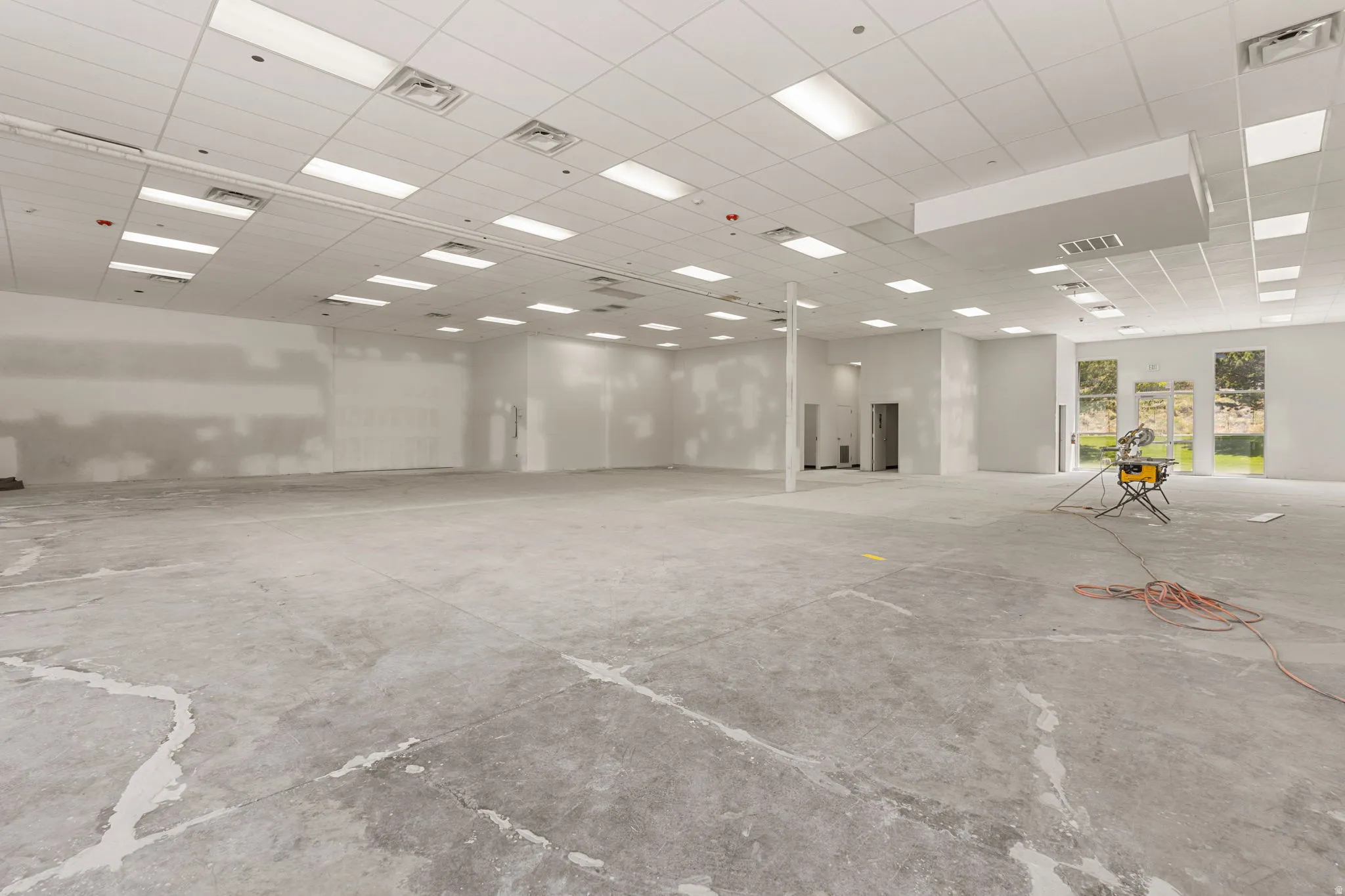Expansive commercial space featuring a drop ceiling with integrated rectangular lighting and a concrete floor