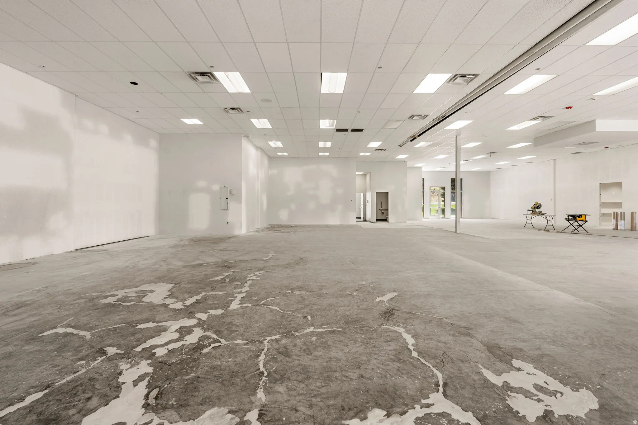 Expansive open-concept commercial space featuring high ceilings with recessed lighting, concrete flooring, and multiple entrances