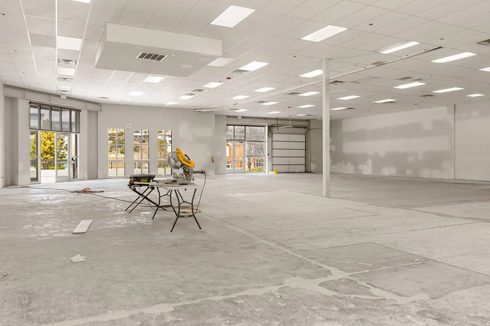Spacious commercial interior featuring a suspended acoustic ceiling with integrated rectangular lighting and a concrete floor