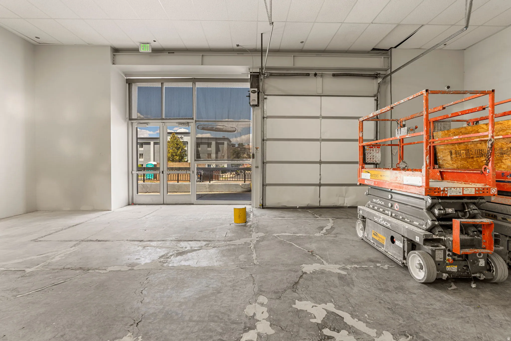 Spacious interior featuring a concrete floor, high ceilings, and a large glass-paned entry door