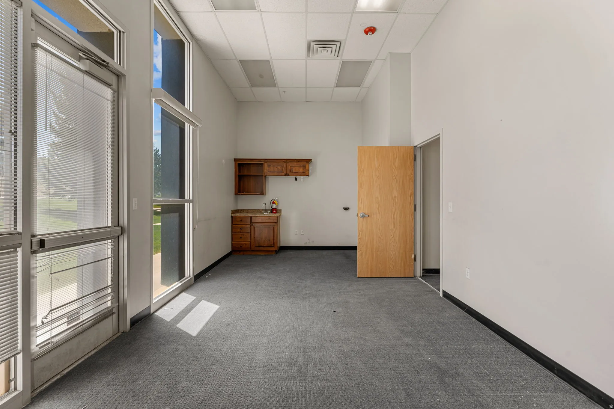 Spacious room featuring multiple large windows, a built-in sink with cabinetry, and light wood-finish doors