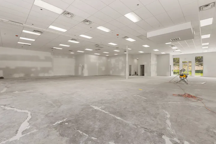 Expansive commercial space featuring a drop ceiling with integrated rectangular lighting and a concrete floor