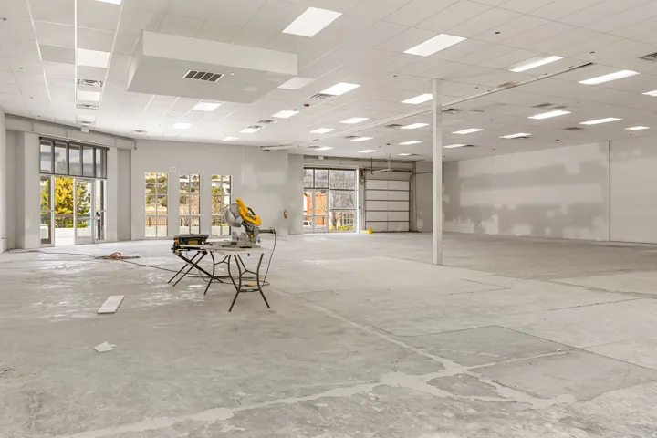 Spacious commercial interior featuring a suspended acoustic ceiling with integrated rectangular lighting and a concrete floor