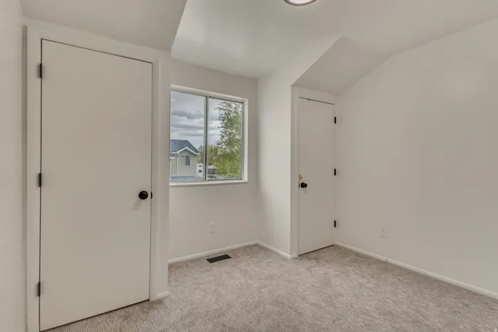 Neutral-toned wall-to-wall carpeting complements a window with views of mature trees