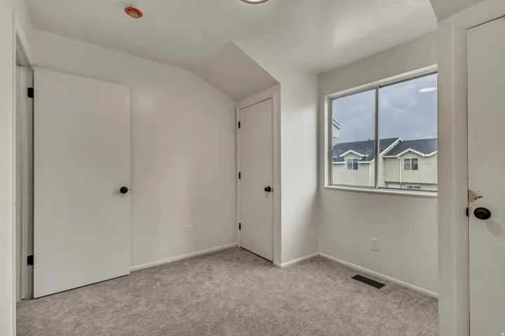 Neutral interior space featuring white walls and a light grey carpet