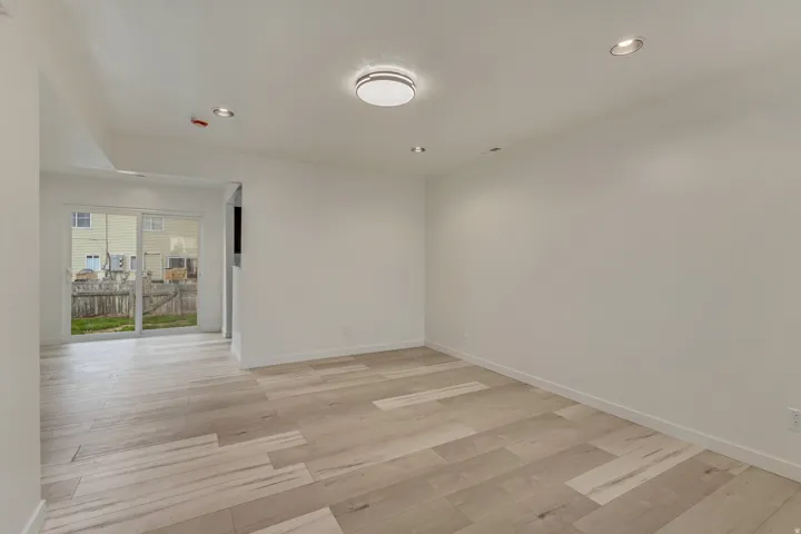 Spacious room featuring light wood-finish flooring, white walls, and a contemporary ceiling light fixture