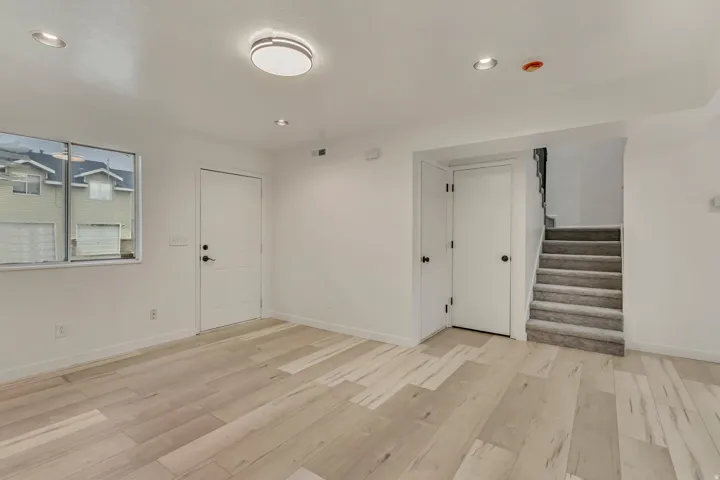 Spacious room featuring light wood-finish flooring, white walls, and a window with exterior views