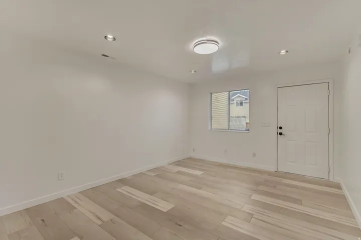 Bright room featuring wood-finish flooring, recessed lighting, and a modern flush-mount ceiling fixture