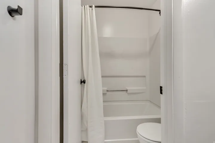 White tub/shower combination with a curved shower rod and matte black hardware