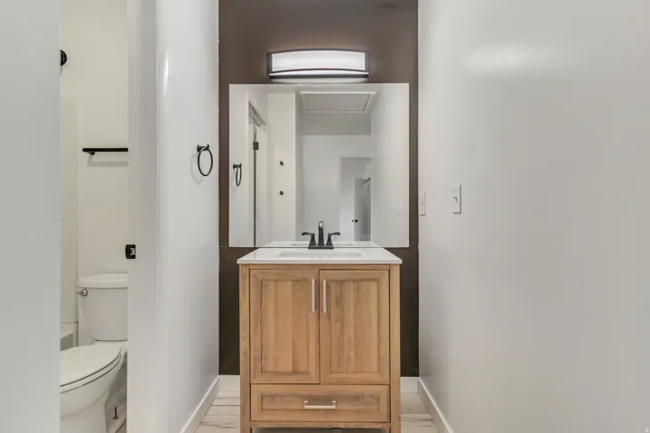 Bathroom vanity with a wood-finish cabinet, white countertop, and rectangular mirror