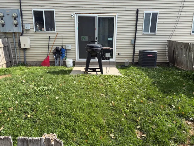 Rear exterior featuring horizontal vinyl siding, a sliding glass door, and two windows