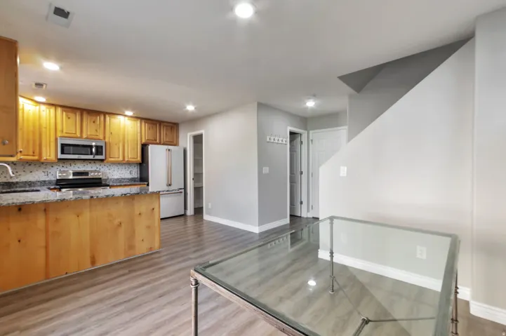 Kitchen featuring wood cabinetry, granite countertops, stainless steel appliances, and a mosaic tile backsplash