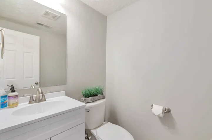 Modern bathroom featuring a white vanity with an integrated sink, brushed nickel faucet, large mirror, and a white toilet