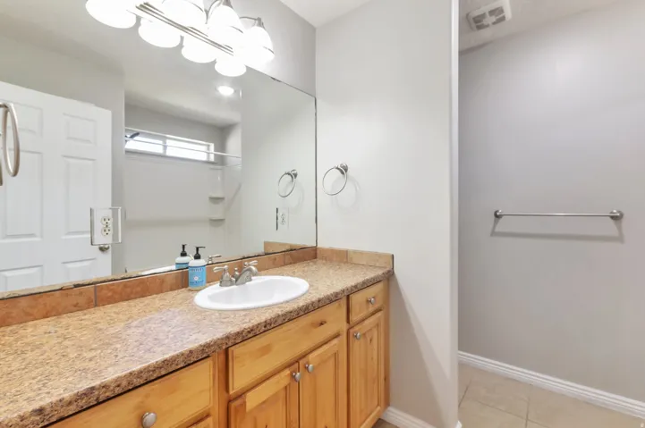Bathroom vanity featuring a light-toned countertop, undermount sink, and wood cabinetry