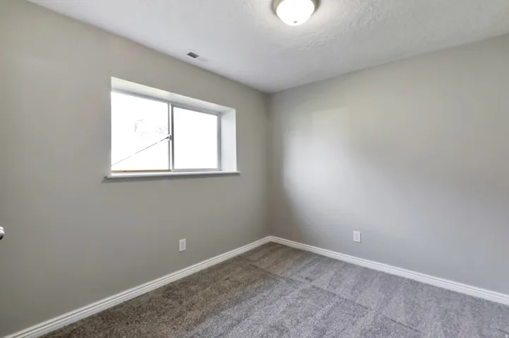 Room featuring neutral gray walls, textured ceiling, and gray carpet flooring