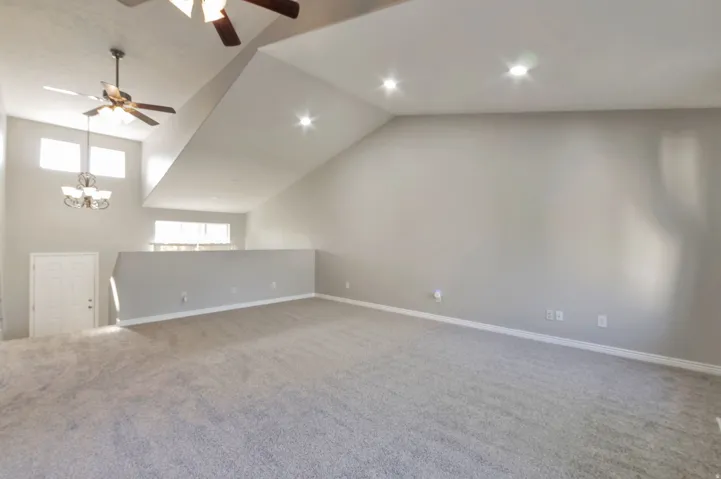 Spacious room featuring vaulted ceilings, recessed lighting, and a ceiling fan