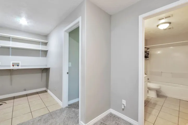 Dedicated laundry area featuring tile flooring, built-in shelving, and utility hookups