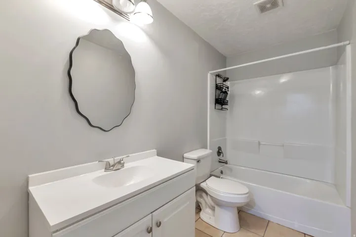 Bathroom featuring a white vanity with integrated sink, chrome faucet, and a contemporary wall-mounted mirror
