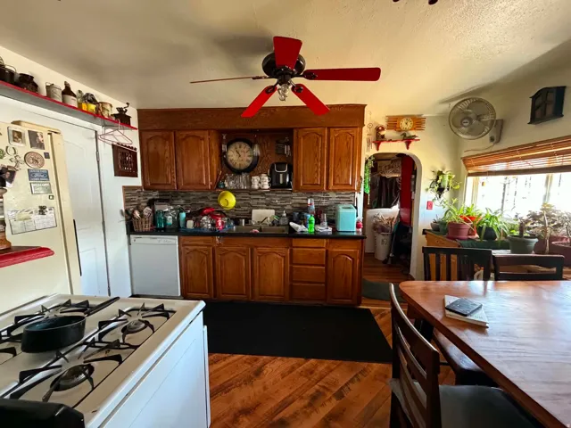 Kitchen featuring wood-finish flooring, wood cabinetry, dark countertops, and a tiled backsplash
