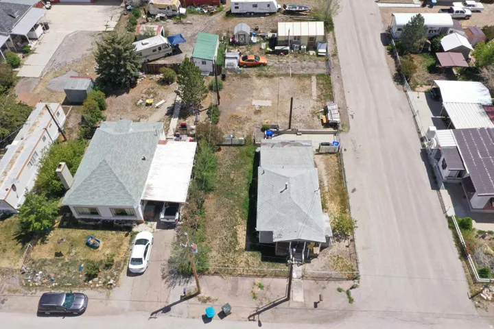 Two distinct single-story residences with pitched shingle roofs and concrete driveways, accompanied by a spacious undeveloped lot