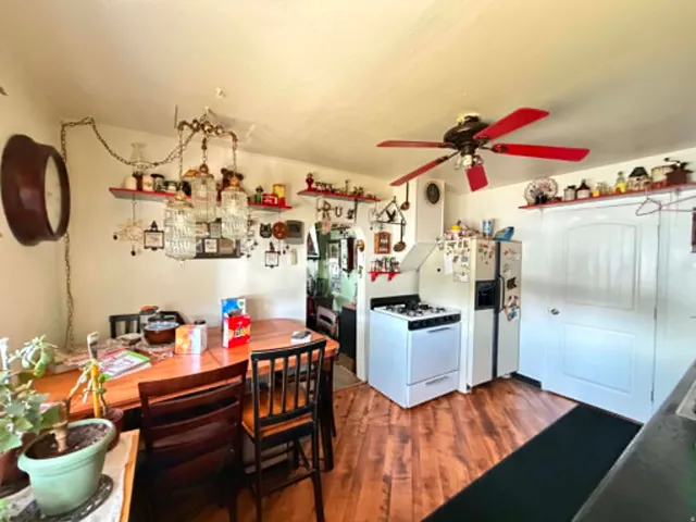 Kitchen area featuring wood-finish flooring, a white gas range, and a white refrigerator