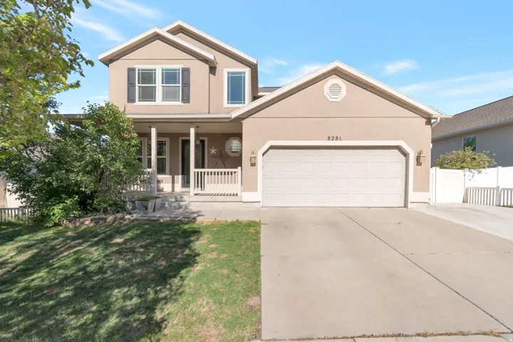 Two-story residence featuring a covered front porch, an attached two-car garage, stucco exterior, and a concrete driveway