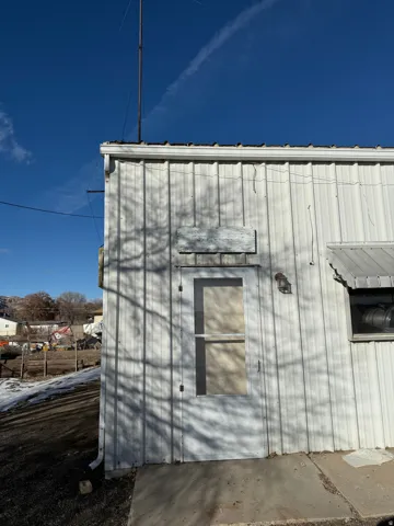 View of property exterior with a metal roof and an outdoor structure