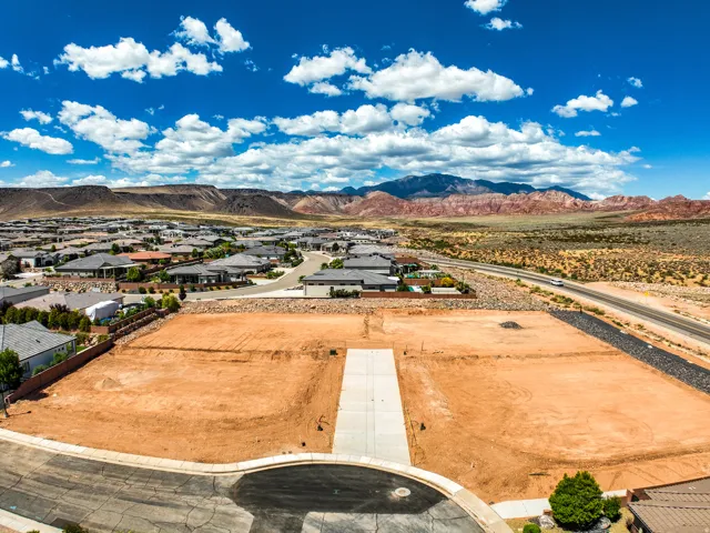 Graded lot featuring a concrete driveway and red earth, surrounded by developed residential properties