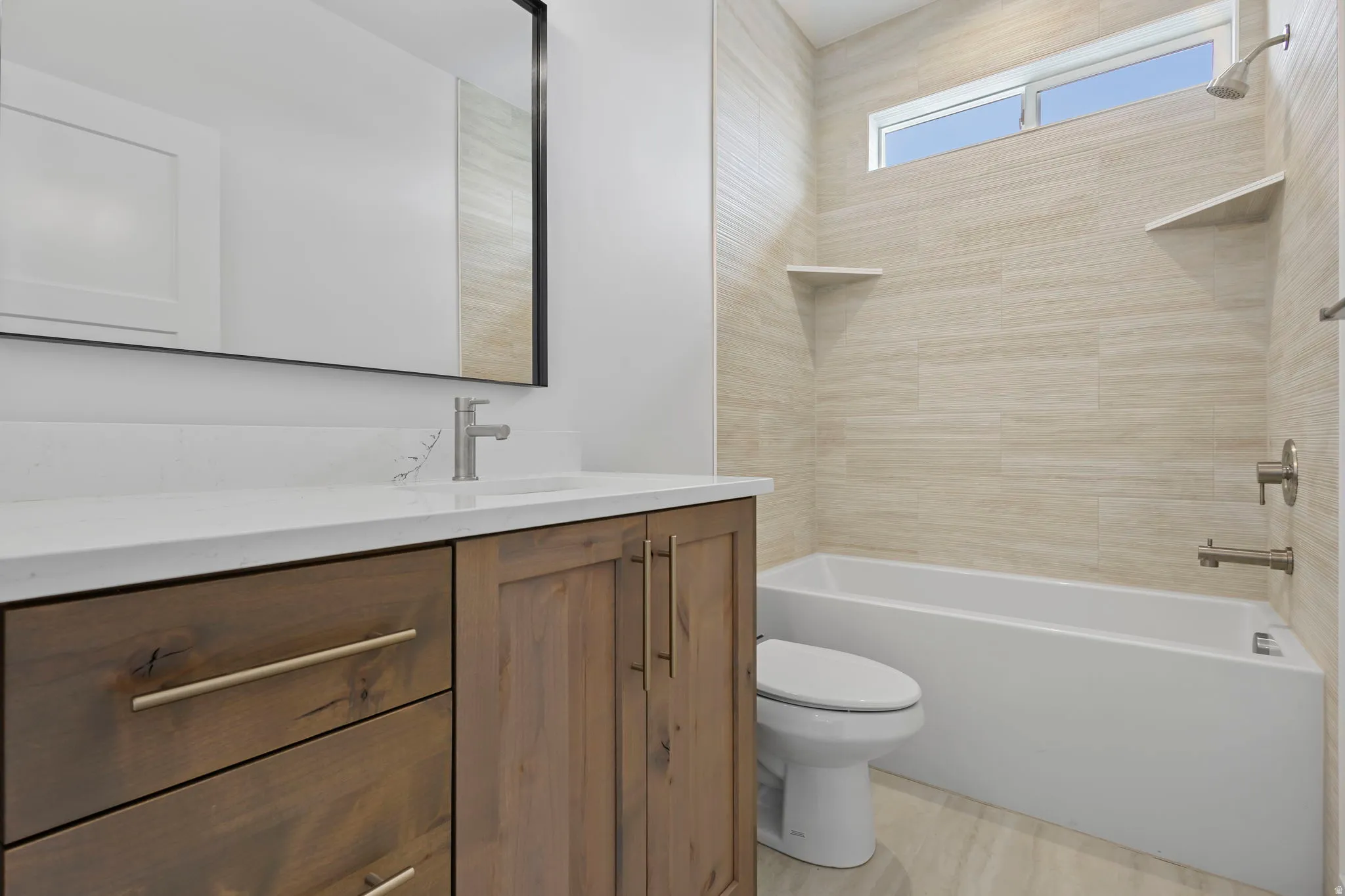 Bathroom featuring a wood-finish vanity with a light-toned countertop, a rectangular undermount sink, and a brushed nickel faucet