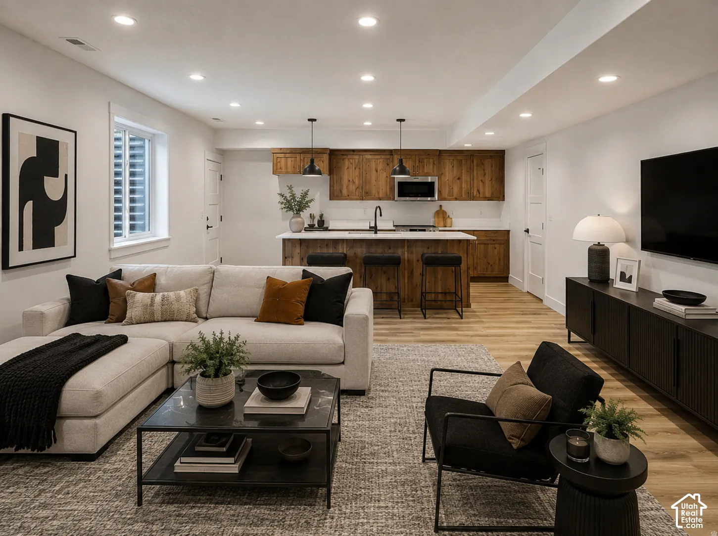 Open-concept living area featuring wood-finish flooring, recessed lighting, and a kitchen with wood cabinetry and a white countertop
