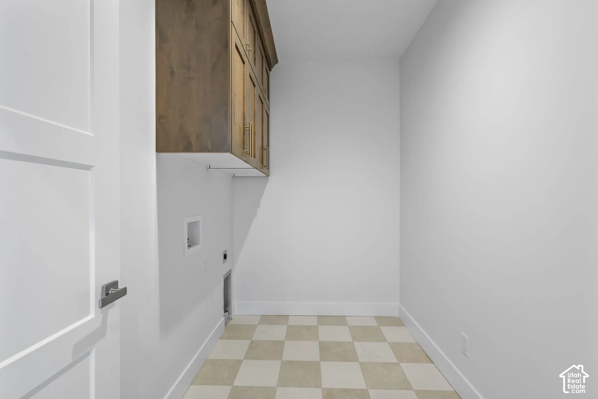 Utility room with checkerboard tile flooring, white walls, and built-in wood-finish cabinetry
