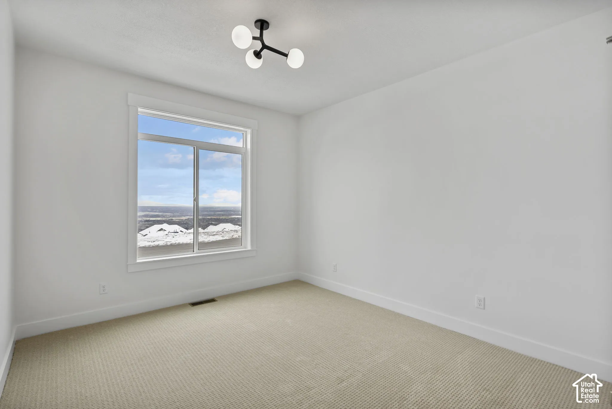 Bright room featuring a large window, neutral wall paint, and a modern ceiling light fixture