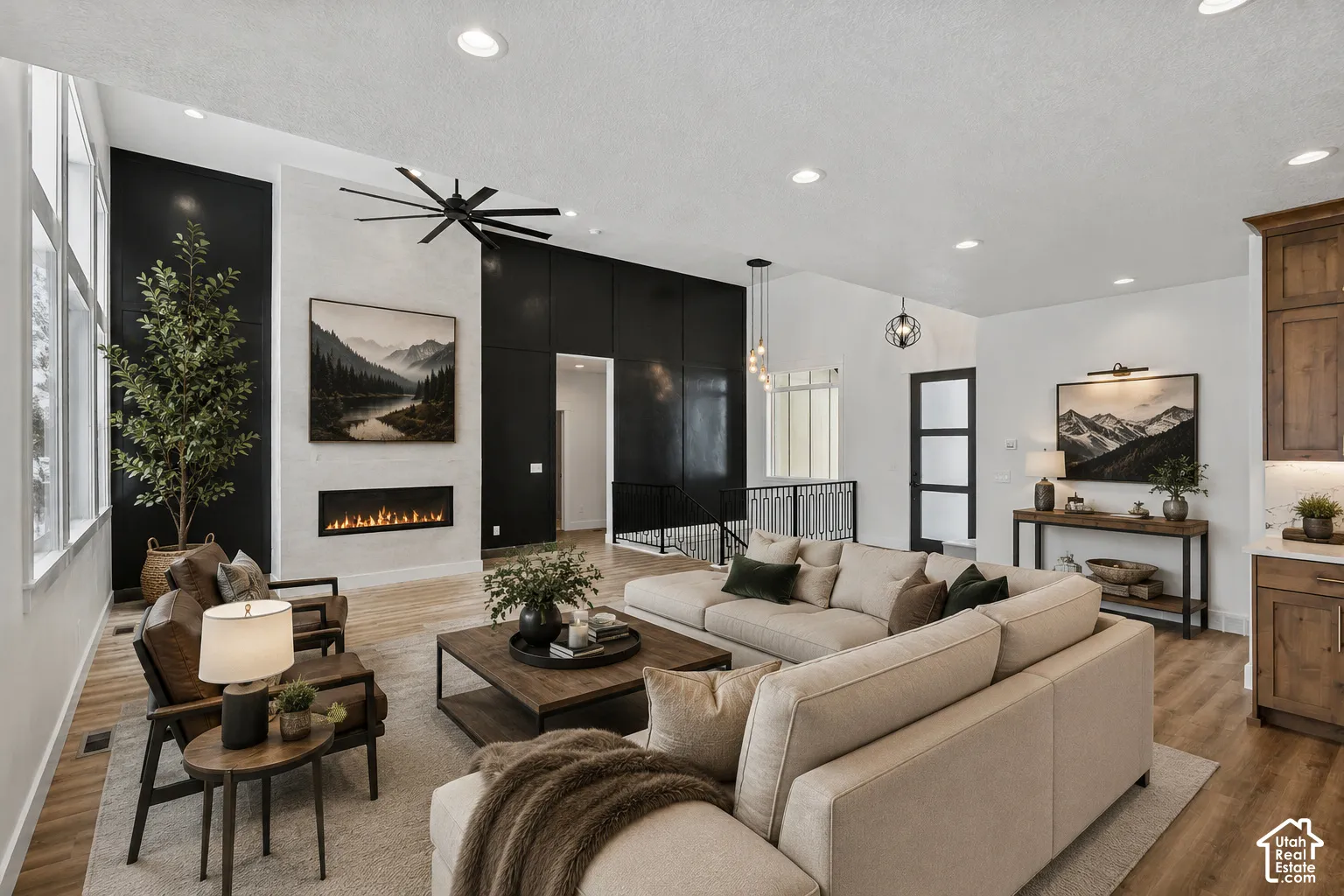 Spacious living area featuring a linear fireplace, vaulted ceiling, large windows, recessed lighting, and wood-finish flooring