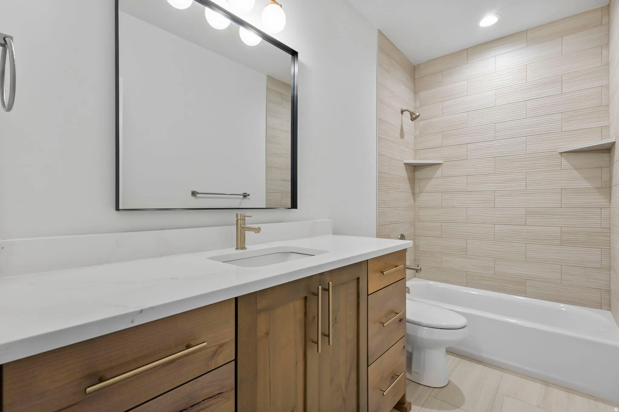 Bathroom featuring a wood-finish vanity with gold-tone hardware, white countertop, and an undermount sink