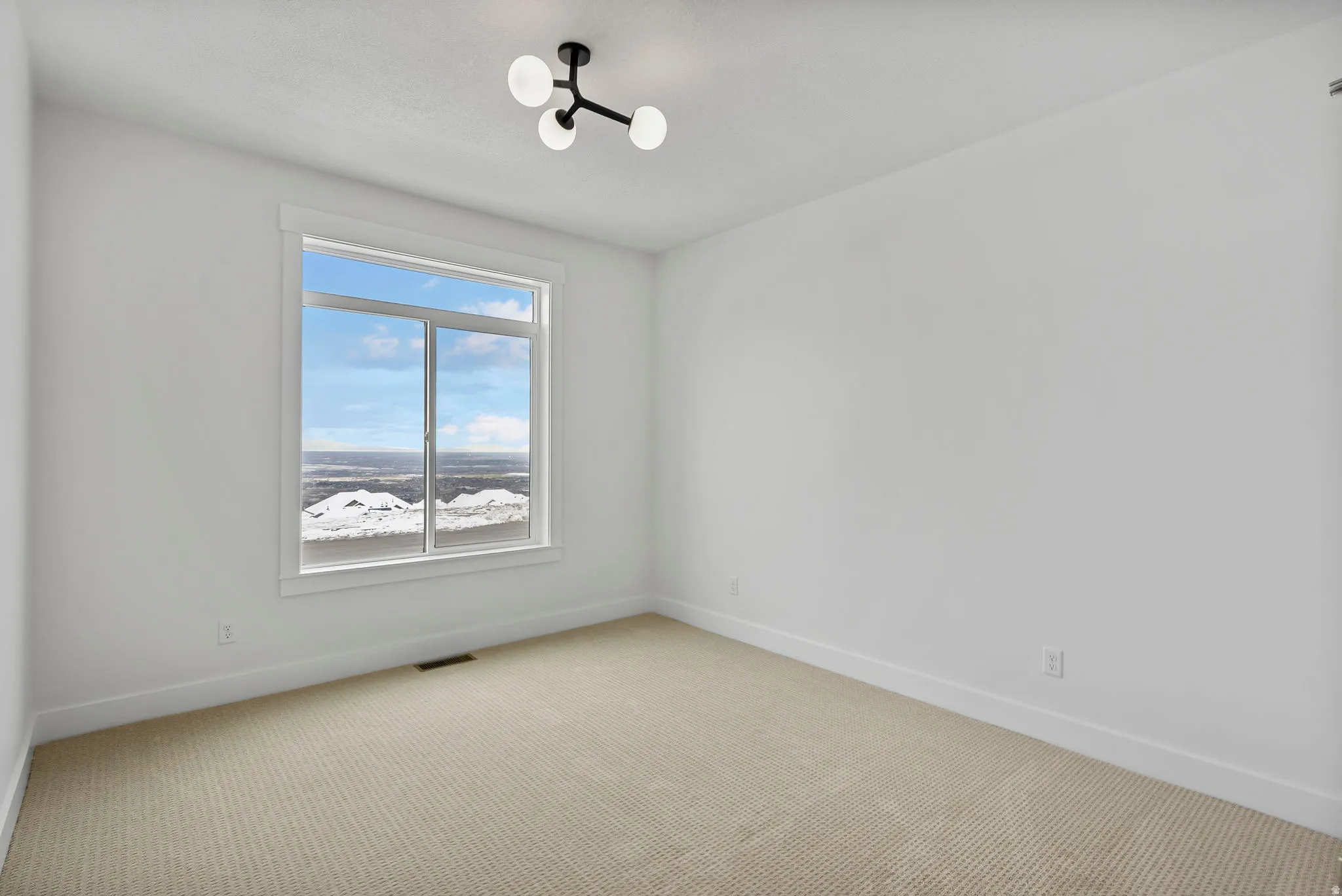Bright room featuring a large window, neutral wall paint, and a modern ceiling light fixture