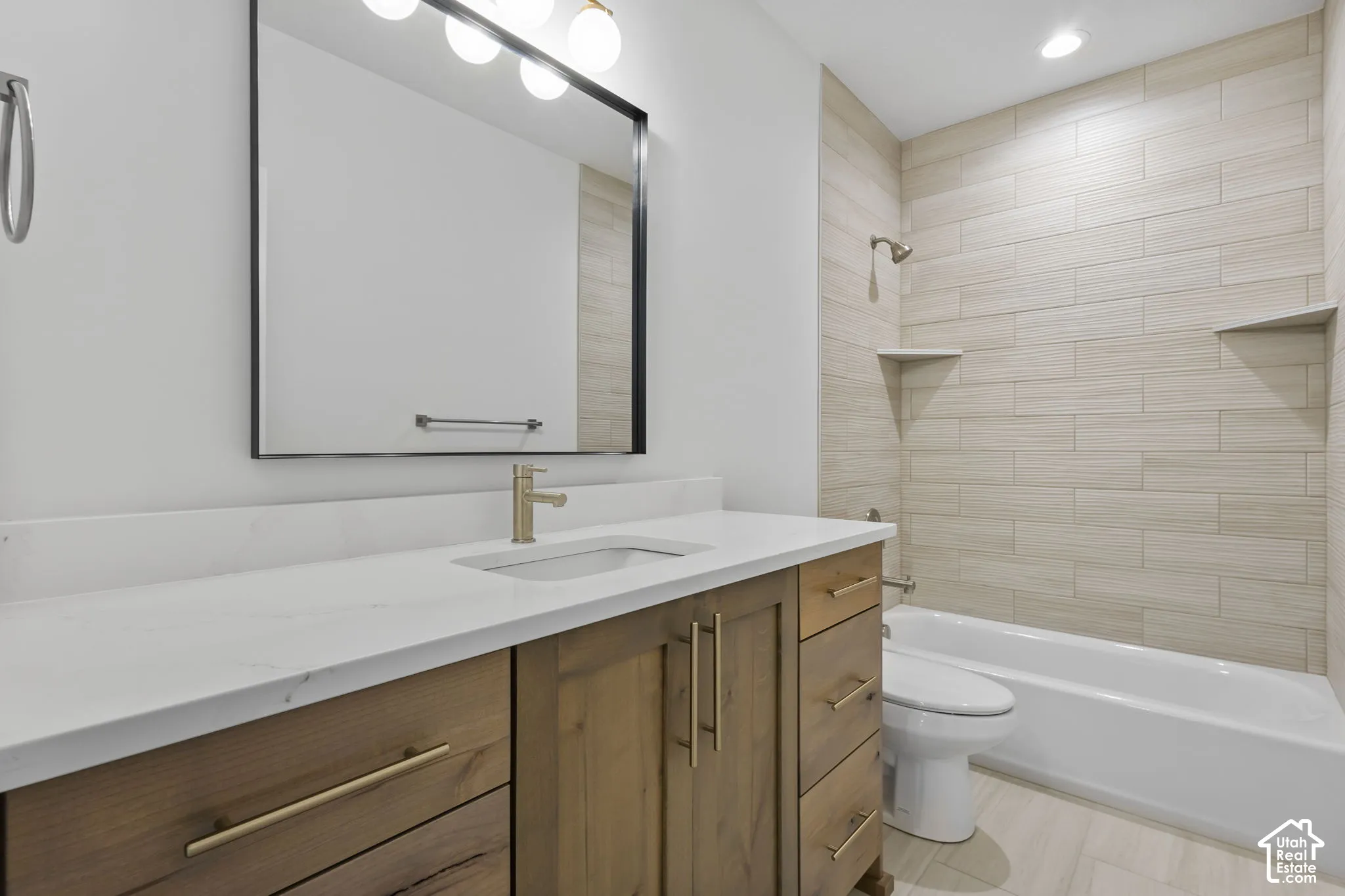 Bathroom featuring a wood-finish vanity with gold-tone hardware, white countertop, and an undermount sink