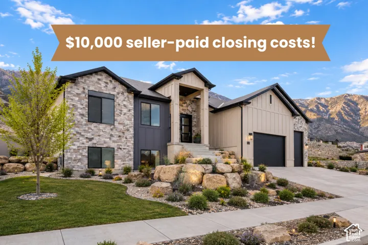 Modern multi-textured exterior featuring stone veneer, vertical siding, an attached three-car garage, and tiered landscape boulders