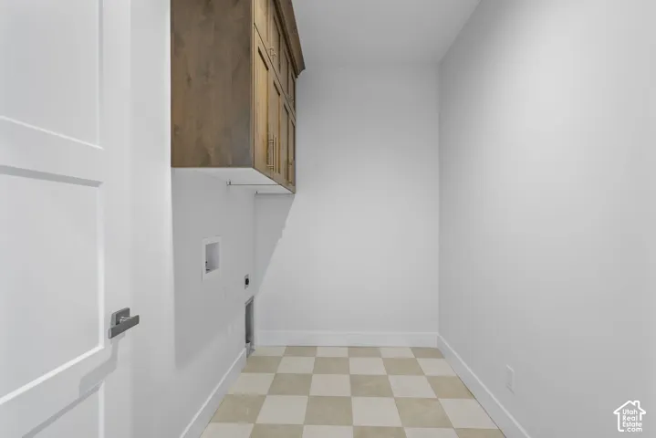 Utility room with checkerboard tile flooring, white walls, and built-in wood-finish cabinetry