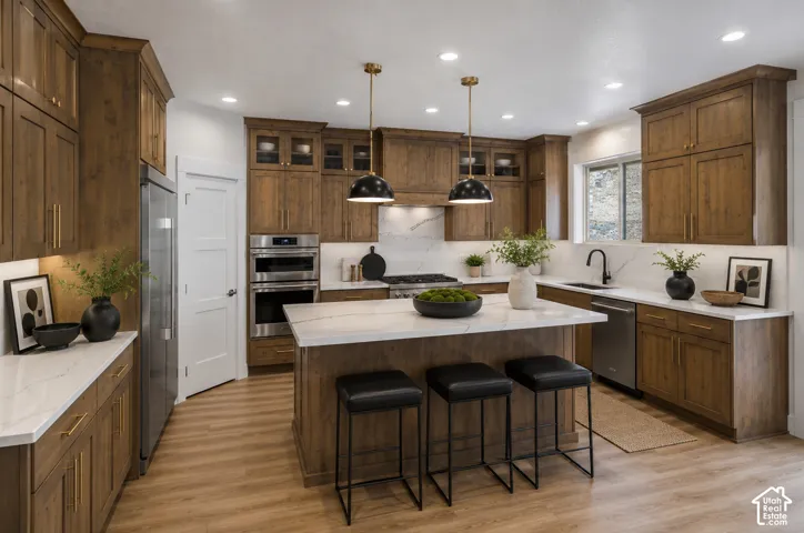 Modern kitchen featuring a large central island with seating, extensive wood cabinetry, light-toned countertops, stainless steel appliances, and recessed lighting