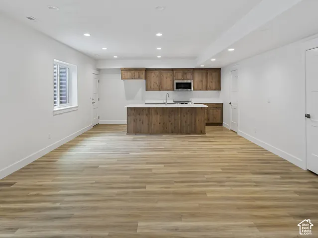 Spacious open-concept room featuring wood-finish flooring, recessed lighting, and a modern kitchen area