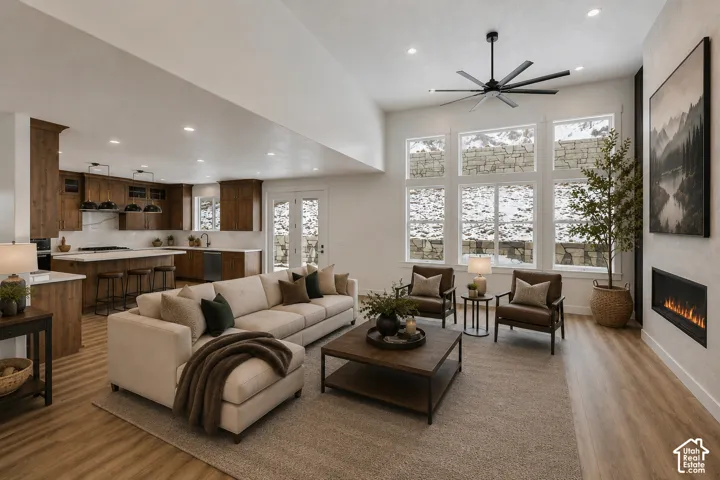 Open-concept living space featuring wood-finish flooring, a contemporary fireplace, and a large multi-pane window array