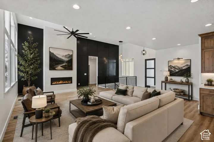 Spacious living area featuring a linear fireplace, vaulted ceiling, large windows, recessed lighting, and wood-finish flooring