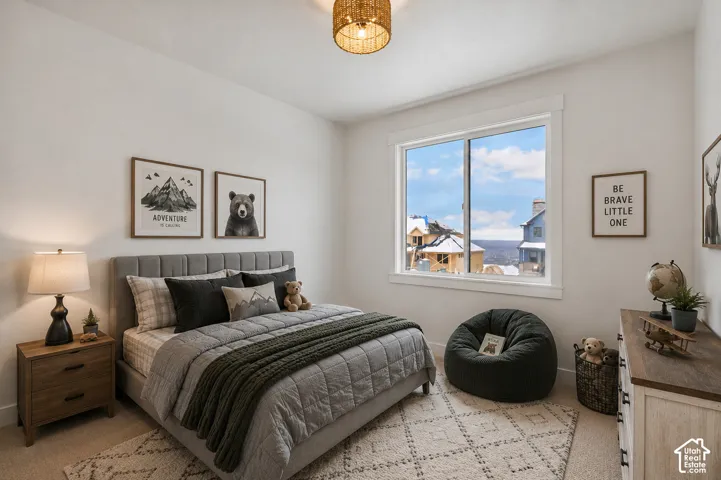 Bright bedroom featuring a large window, neutral wall tones, and overhead lighting