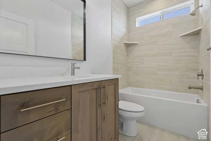 Bathroom featuring a wood-finish vanity with a light-toned countertop, a rectangular undermount sink, and a brushed nickel faucet