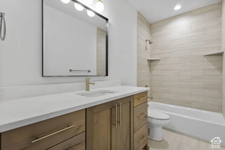 Bathroom featuring a wood-finish vanity with gold-tone hardware, white countertop, and an undermount sink