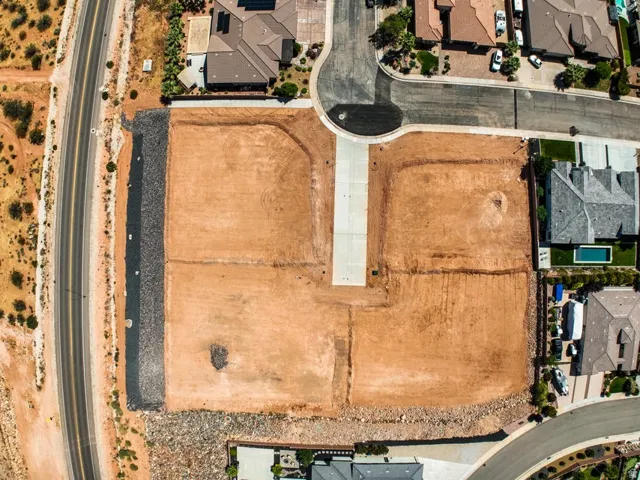 Expansive graded lot featuring multiple building pads, a paved access road, and established surrounding properties