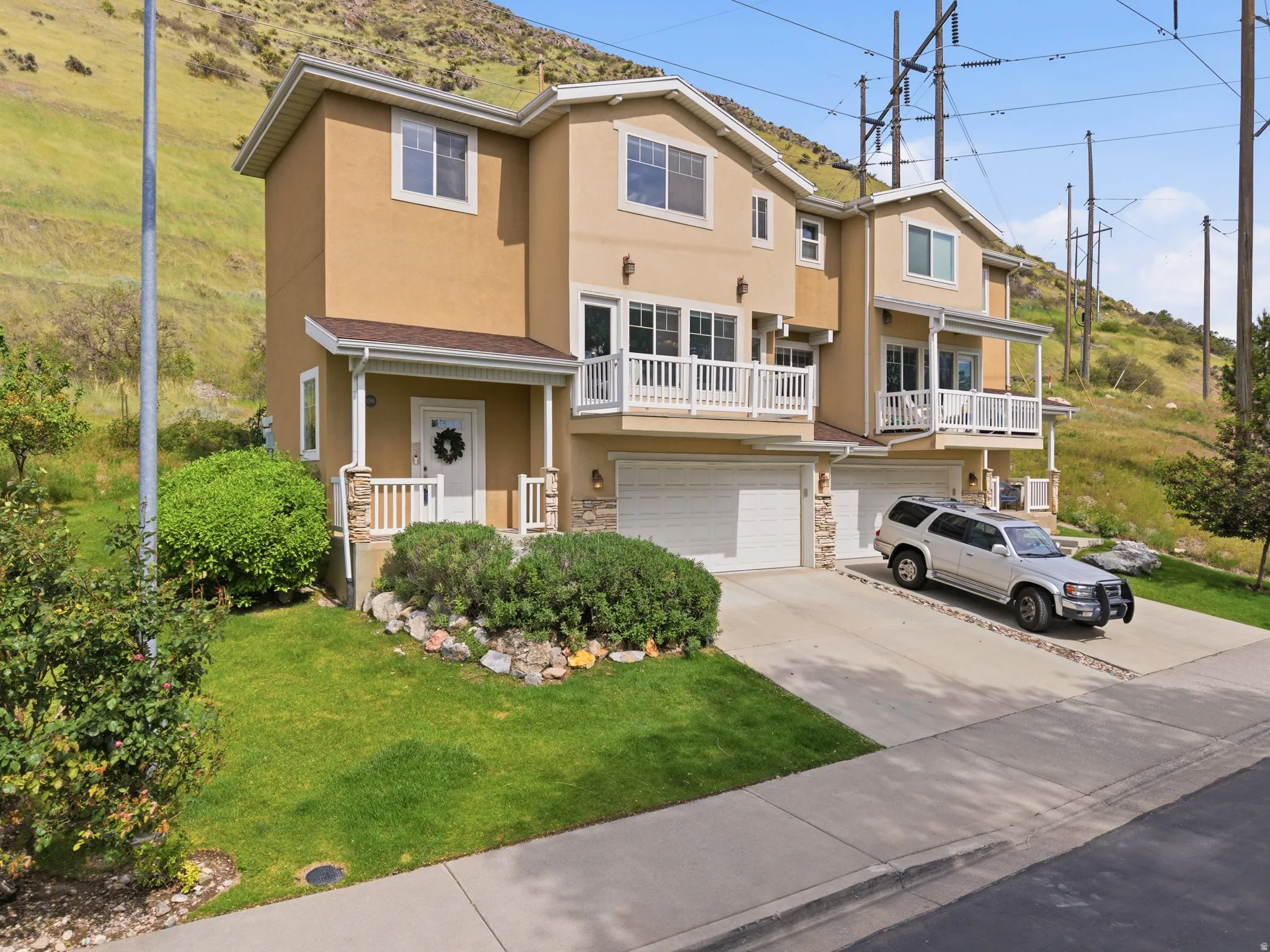 Stucco exterior with stone accents, featuring a two-car garage, covered entry, and upper-level balcony