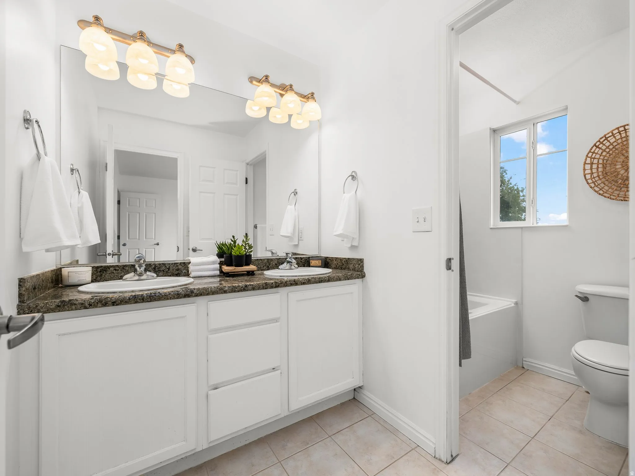 Dual vanity with white cabinetry, a dark speckled countertop, and under-mount sinks